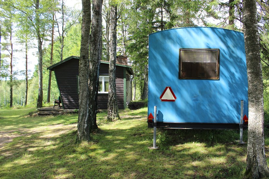 Vy mot stugan och blå boden från söder